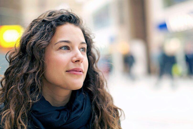 nainen kaupungilla katsoo levollisesti oikealle