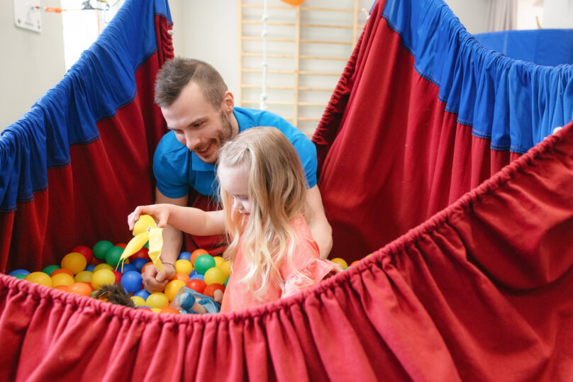 Coronaria kuntoutuspalvelut toimintaterapian lapsiasiakas etsii terapeutin kanssa pallomerestä esineitä.