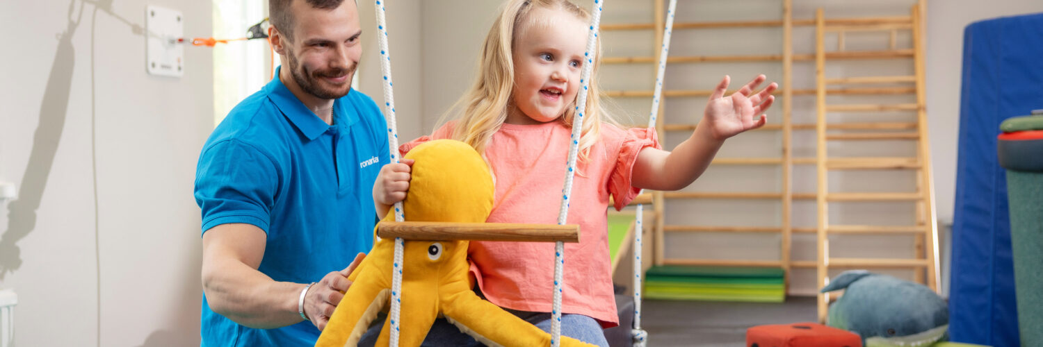 Coronaria kuntoutuspalvelut toimintaterapian lapsiasiakas on pitkässä keinussa pehmolelun kanssa.