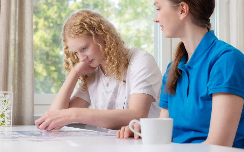 Coronaria kuntoutuspalvelut psykiatrinen toimintaterapia, teinityttö tekee terapeutin kanssa pöydän ääressä tehtävää.
