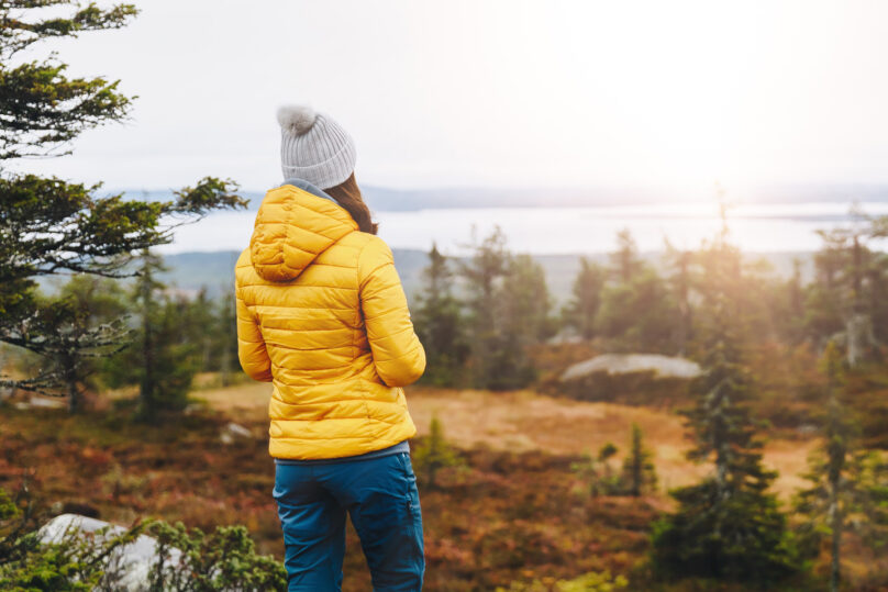 Nainen katsoo ruskamaisemaa tunturin huipulla Lapissa syksyllä.