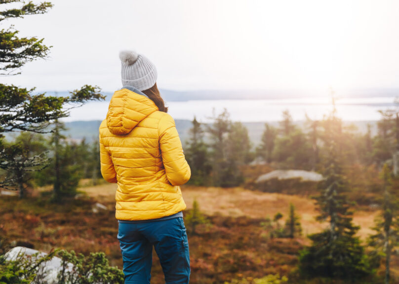 Nainen katsoo ruskamaisemaa tunturin huipulla Lapissa syksyllä.