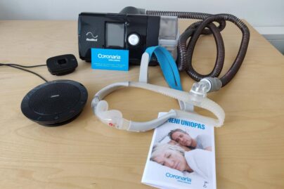 Pöydällä Resmedin CPAP-laite, maski ja pieni uniopas