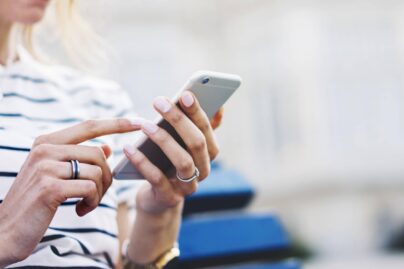 Nainen istuu ja pitelee puhelinta kädessään.