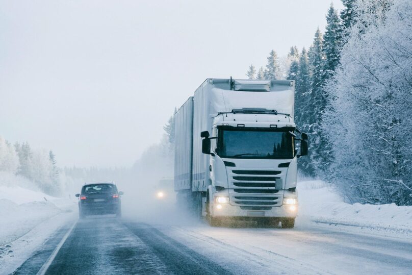 Valkoinen rekka-auto ajaa Lapissa lumisella tiellä talvella.