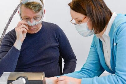 asiakas Mikko Heimo sovittaa CPAP-maskia hoitajan kanssa