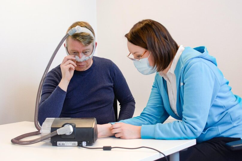 asiakas Mikko Heimo sovittaa CPAP-maskia hoitajan kanssa