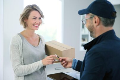 Asiakas vastaanottaa Coronarian uniklinikan verkkokaupasta tilatun paketin lähetiltä.