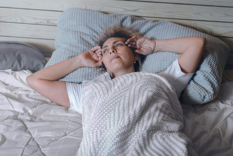 Nainen makaa sängyssä hereillä