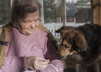 Mummo syöttää koiralle herkkua.