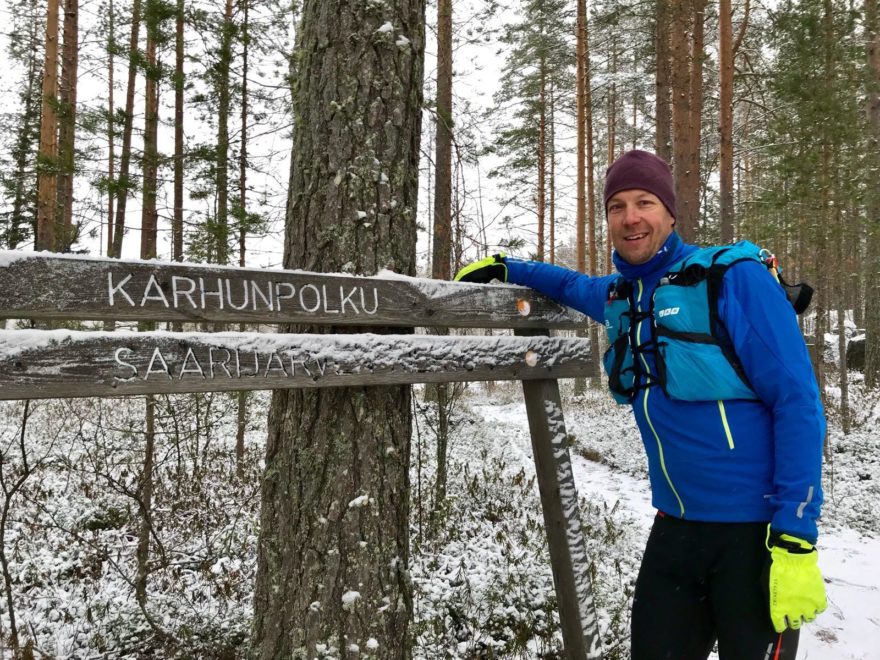Posio liikkuu -hyvinvointikampanjan suojelija Mikko Peltola nojaa kylttiin metsässä.