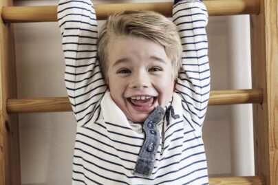 Poika roikkuu puolapuissa ja nauraa.