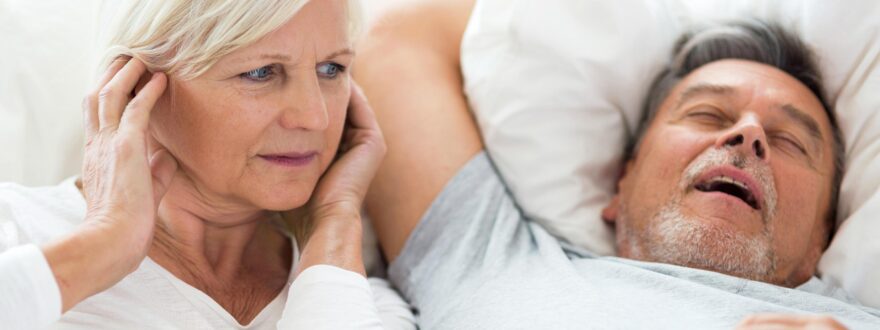 Mies kuorsaa ja nainen pitää käsiä korvilla.