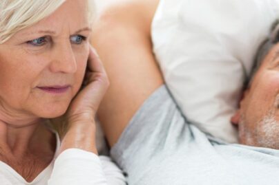 Mies kuorsaa ja nainen pitää käsiä korvilla.