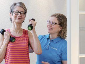 Vanhempi naisasiakas jumppaa fysioterapeutin ohjeistaessa