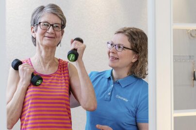 Vanhempi naisasiakas jumppaa fysioterapeutin ohjeistaessa