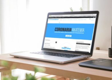 Pöydällä kannettava tietokone, jossa näkyvissä Coronaria Akatemian verkkosivut.