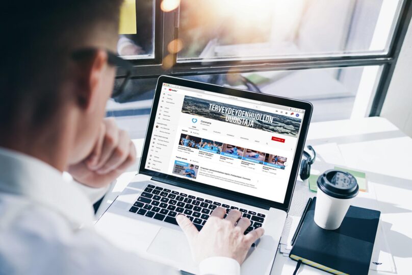 Mies istuu kannettavan tietokoneen äärellä ja selaa Coronarian Youtube sivua.