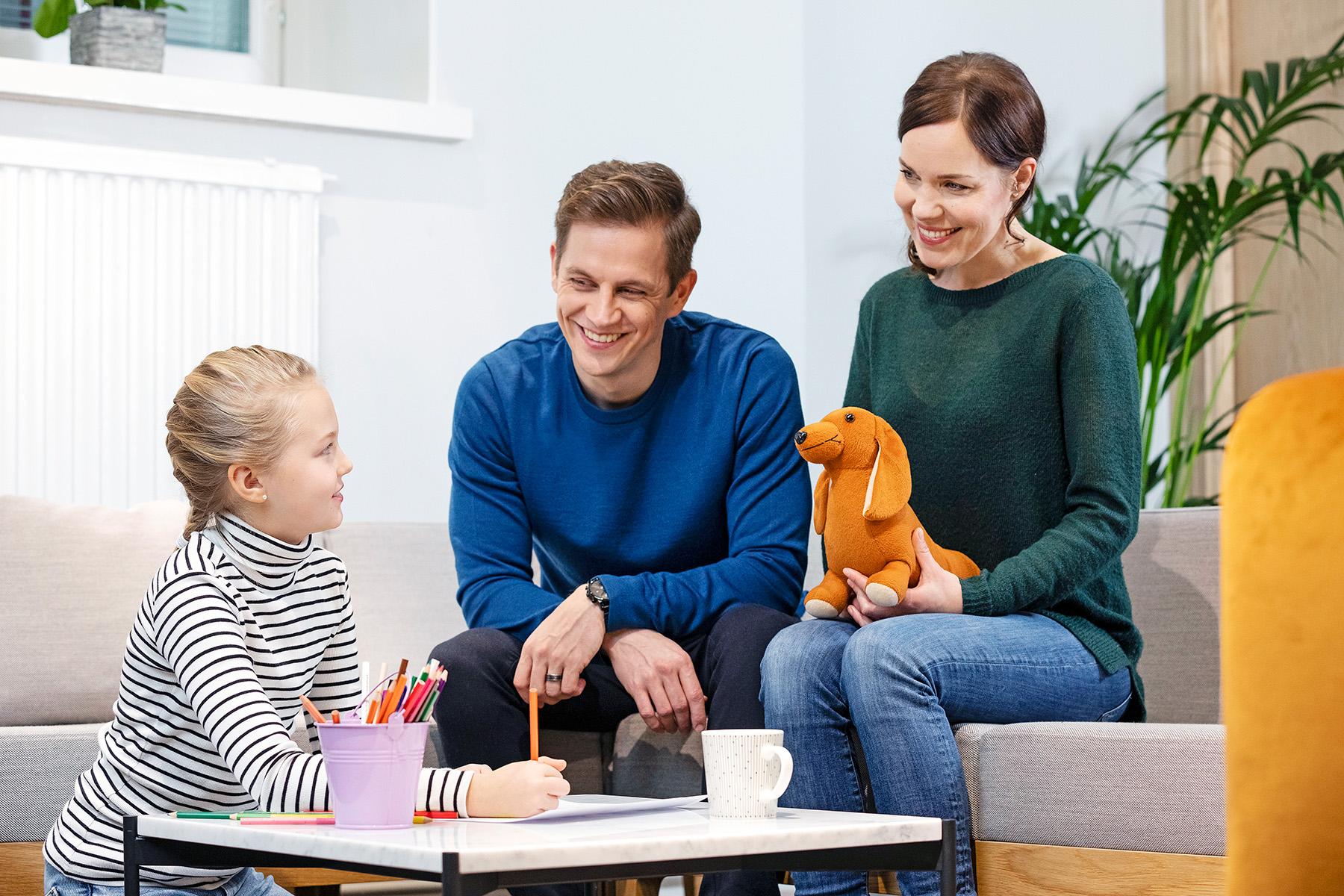Tyttö ja vanhemmat pöydän ääressä.