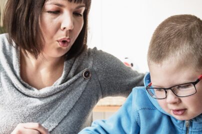 Coronaria Kuntoutuksen puheterapeutti muodostaa huulillaan äännettä ja poika katsoo tablettia.