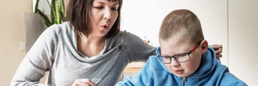 Coronaria Kuntoutuksen puheterapeutti muodostaa huulillaan äännettä ja poika katsoo tablettia.