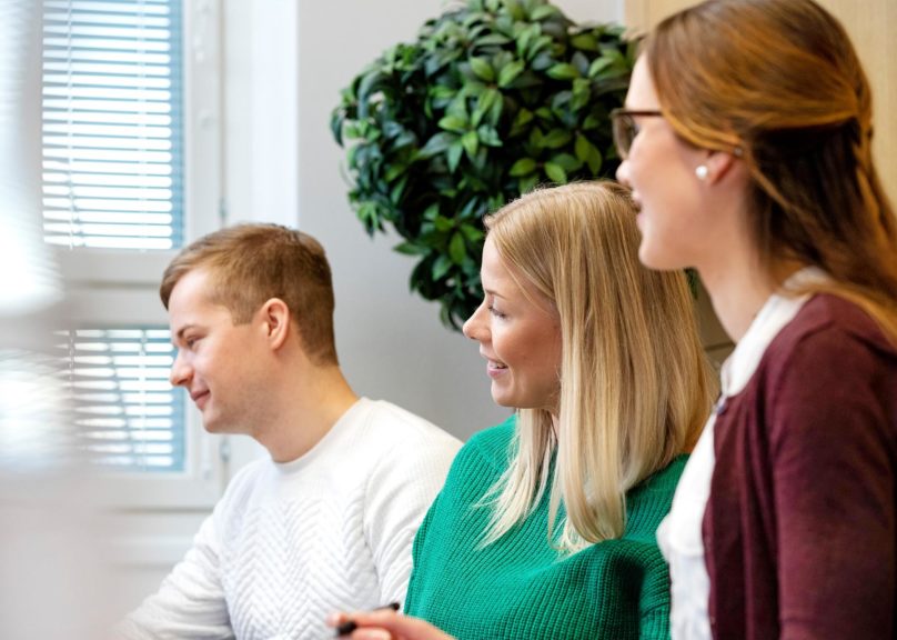 Coronarian kolme toimistotyöntekijää katsoo vasemmalle.