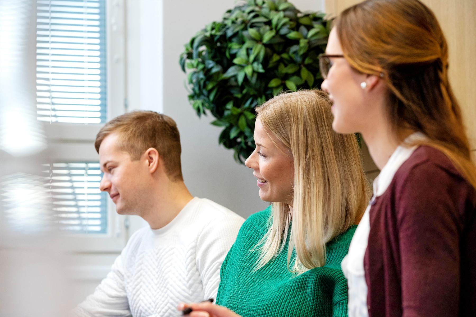 Coronarian kolme toimistotyöntekijää katsoo vasemmalle.
