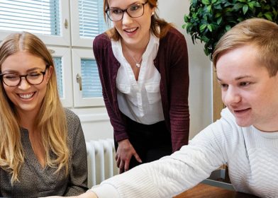 kolme työntekijää kokoushuoneessa