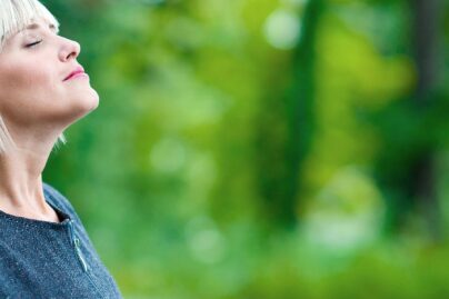 Vaalea nainen ulkona hengittää raikasta ilmaa.