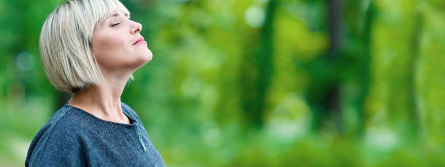 Vaalea nainen ulkona hengittää raikasta ilmaa.