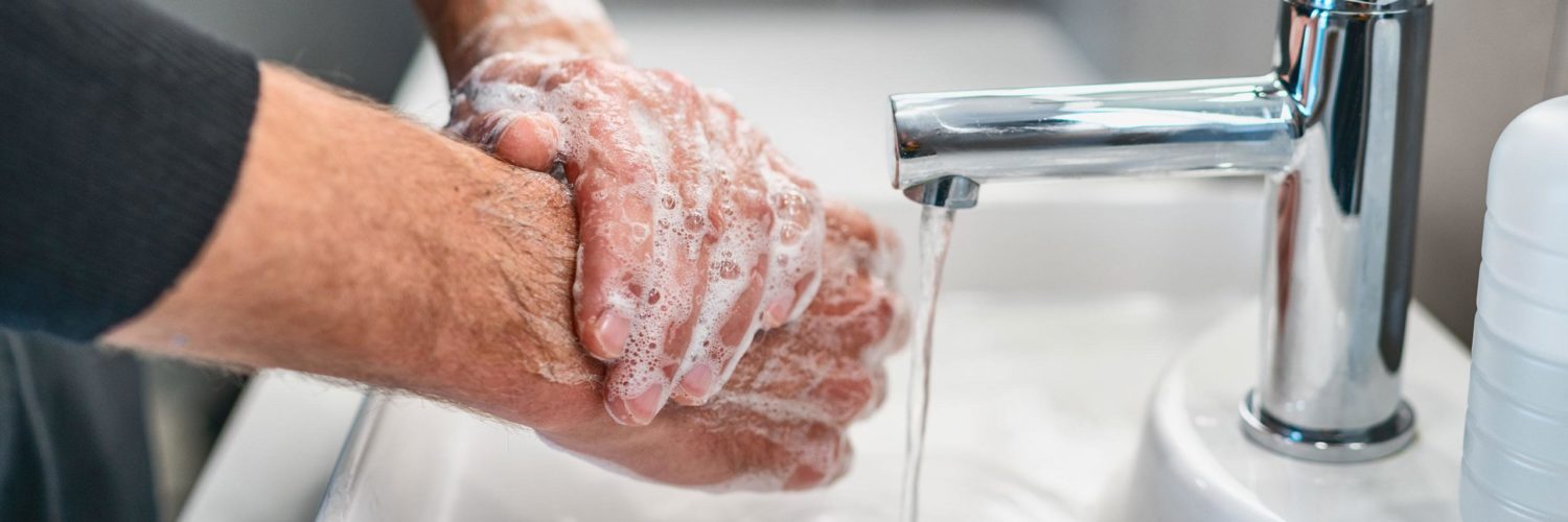 Mies pesee käsiä vesihanan alla