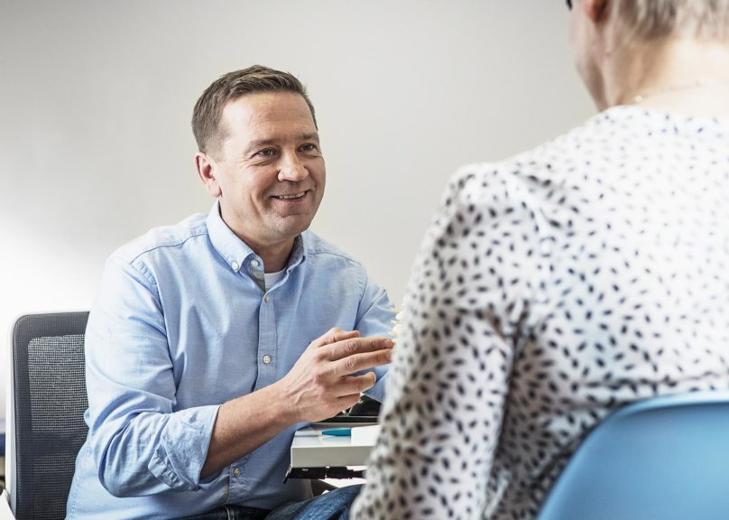 Mieslääkäri ja naispotilas vastaanotolla pöydän ääressä