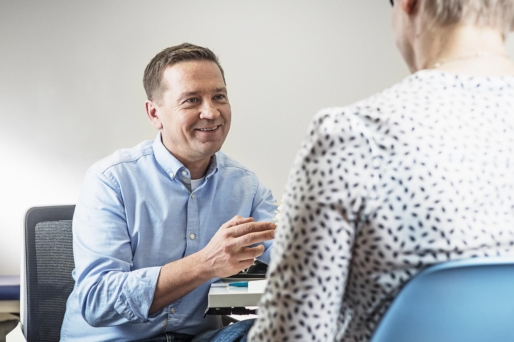 Mieslääkäri ja naispotilas vastaanotolla pöydän ääressä