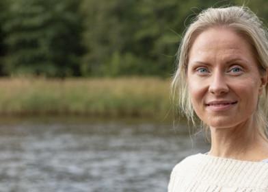 Nainen seisoo vesistön rannalla.
