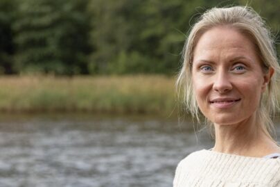 Nainen seisoo vesistön rannalla.