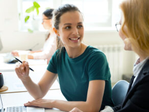 työpari toimistolla, taustalla näkyy avokonttori