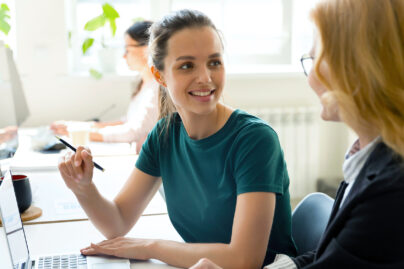 työpari toimistolla, taustalla näkyy avokonttori