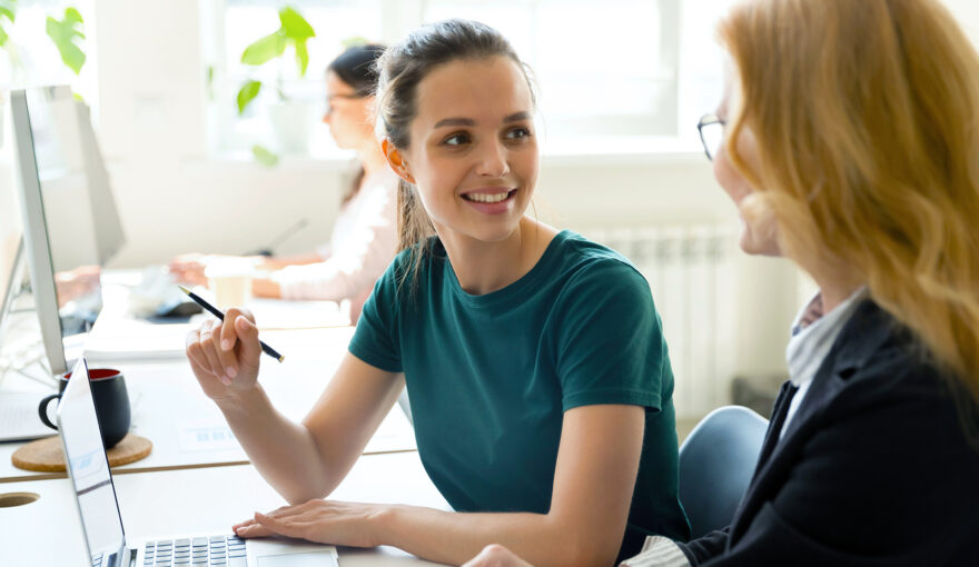 työpari toimistolla, taustalla näkyy avokonttori