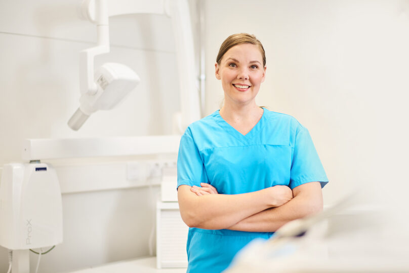 Suun terveyden ammattilainen katsoo kameraan ja hymyilee.