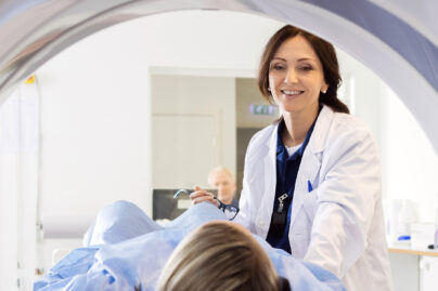 Puolikuvassa hymyilevä naislääkäri ja potilas menossa kuvantamistutkimukseen