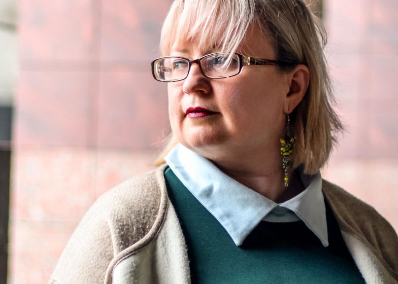 nainen katsoo sivulle lahikuvassa kaupunkimiljoossa