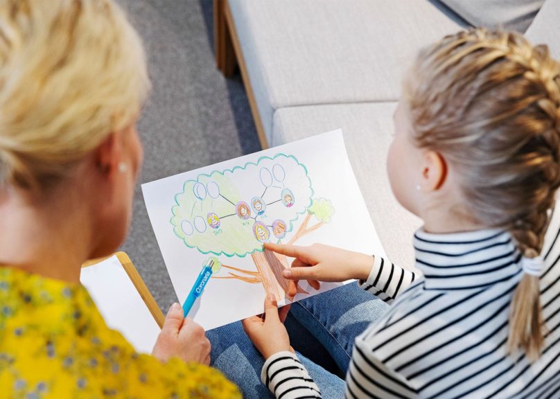 terapeutti ja lapsi katsovat piirustusta yhdessa