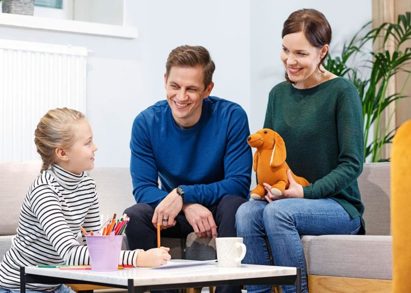 perhe keskustelee terapeutin kanssa sohvalla
