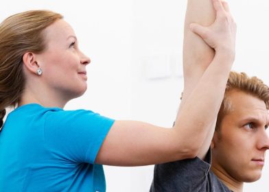 Fysioterapeutti tekee asiakkaalle fysioterapian vastaanotolla passiivisia venytyksiä.