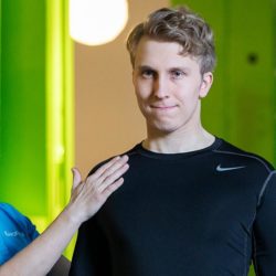 Naisfysioterapeutti ohjaa miesasiakkaan liikettä kuntosalilla.