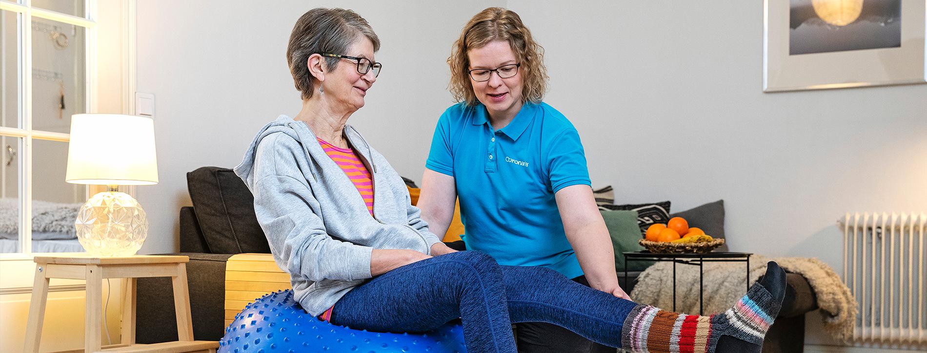 Coronarian seniorifysioterapian fysioterapeutti ohjaa seniorinaisasiakasta fysioterapialiikkeessä kotiympäristössä.