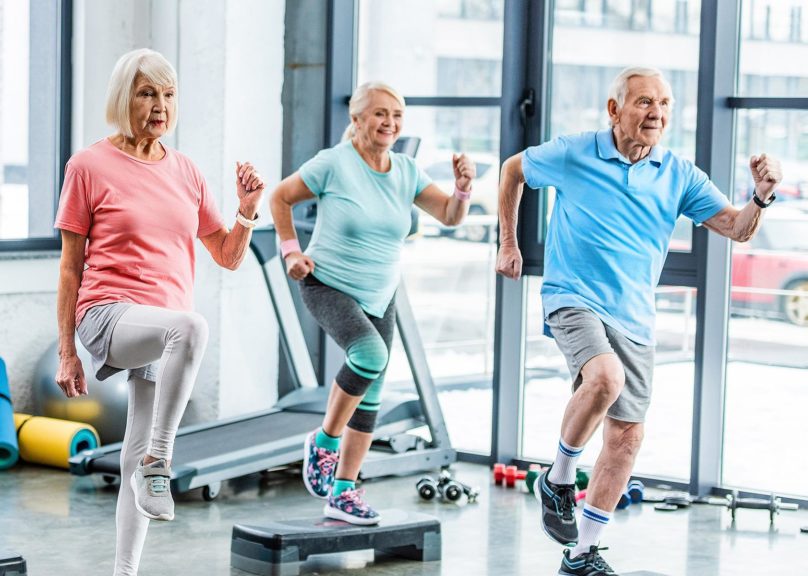 Kaksi seniorinaista ja yksi seniorimies jumppaavat.