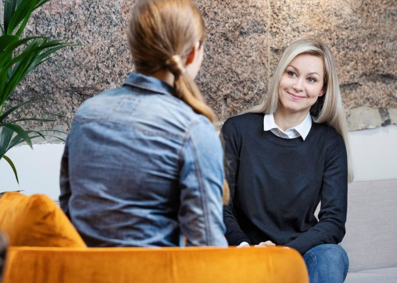 Coronaria työelämäpalveluiden asiakastilanne, jossa kaksi nuorta naista istuu nojatuoleissa ja keskustelee.