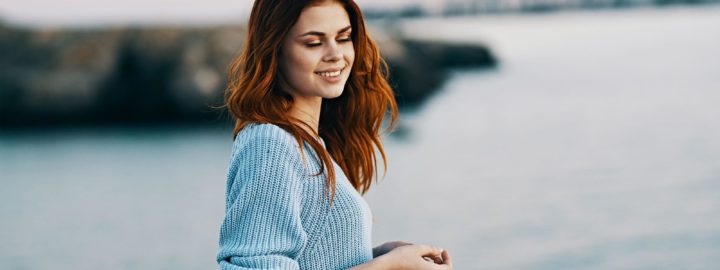 nuori nainen ulkona hymyilee veden aarella