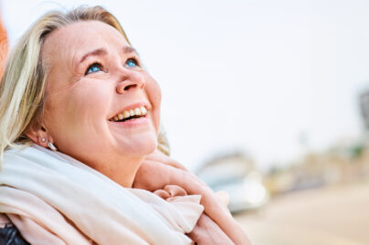 Iloinen nainen katsoo toiveikkaasti yläviistoon.